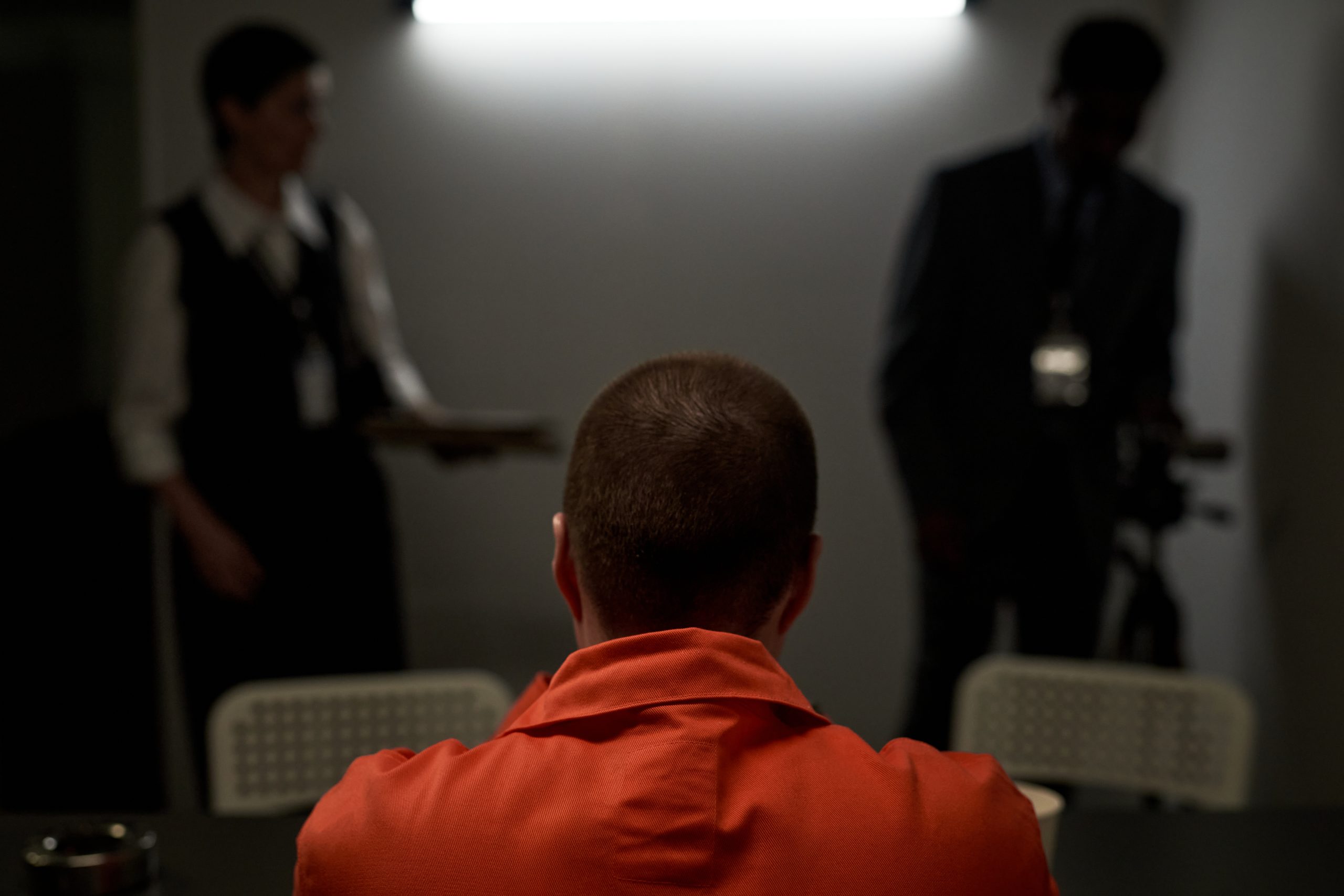 Caucasian Young Adult Woman Sitting in Interrogation Room Facing Law Enforcement